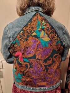 A lady showing the back of her embroidered denim jacket using a scarf panel
